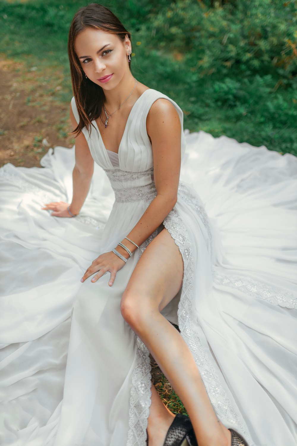 woman in white sleeveless dress sitting on white textile