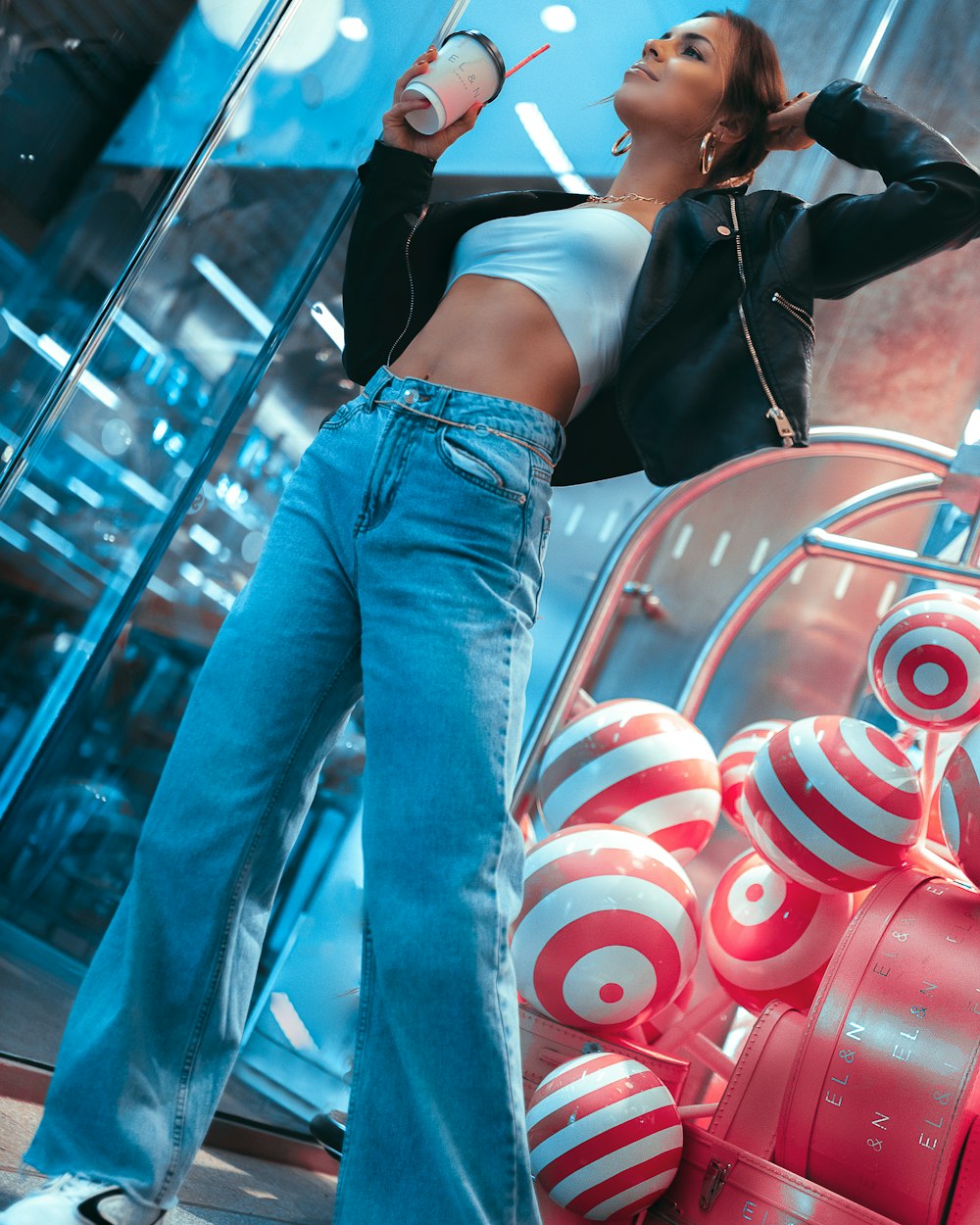 woman in black crop top and blue denim jeans standing beside red and black train during