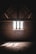 A dimly lit attic with exposed wooden beams and a brick wall. Sunlight filters through a latticed window, casting patterned shadows on the dusty wooden floor.