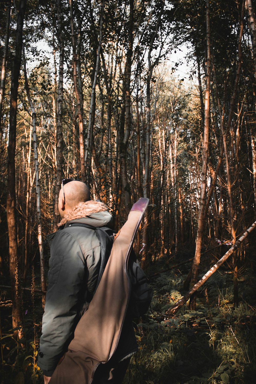 man in black jacket and brown hat standing in the middle of forest during daytime