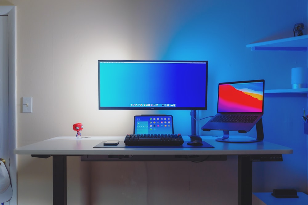 Monitor de computadora de pantalla plana negro sobre escritorio de madera blanca
