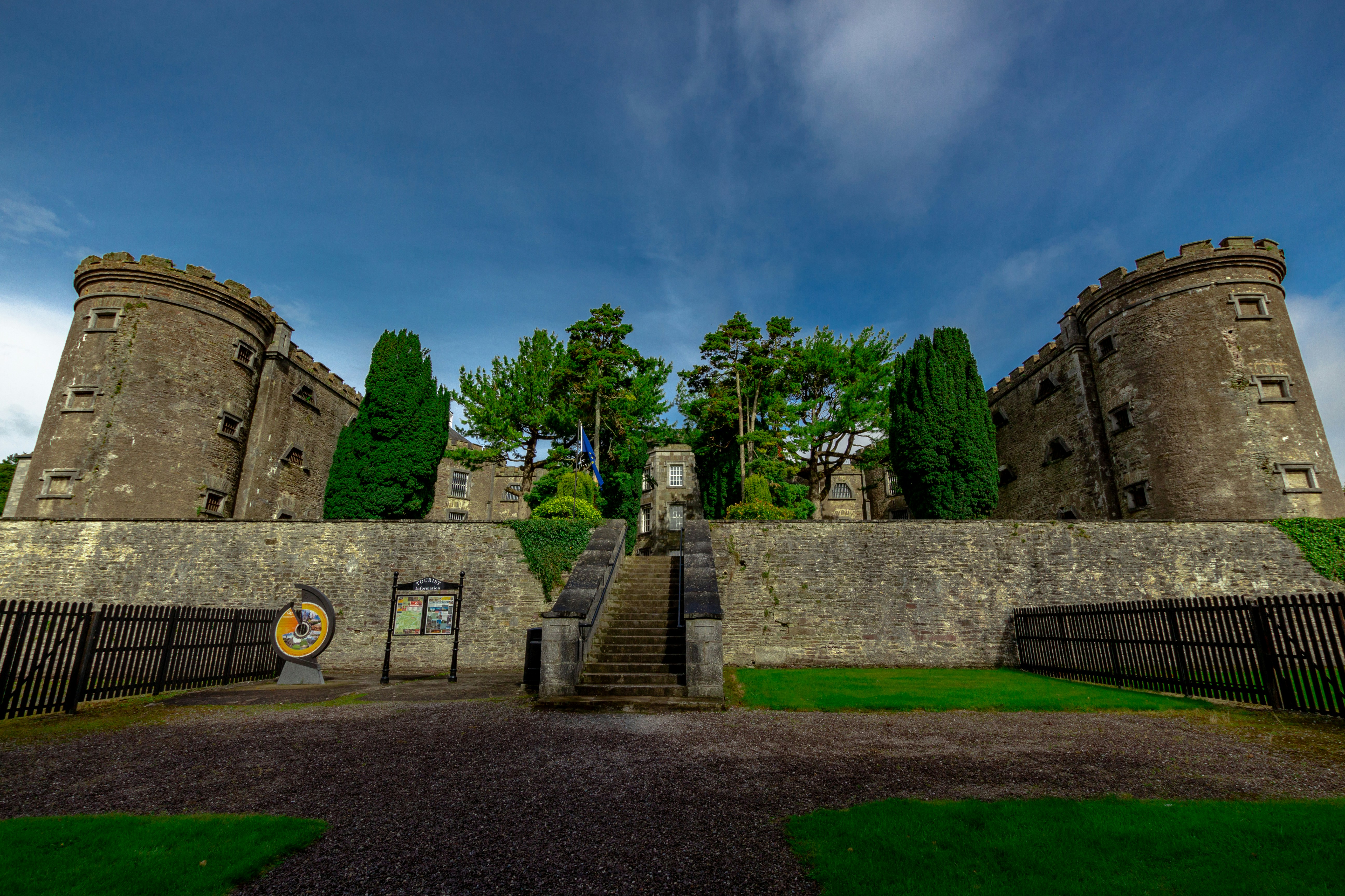 green grass field near gray concrete building under blue sky during daytime