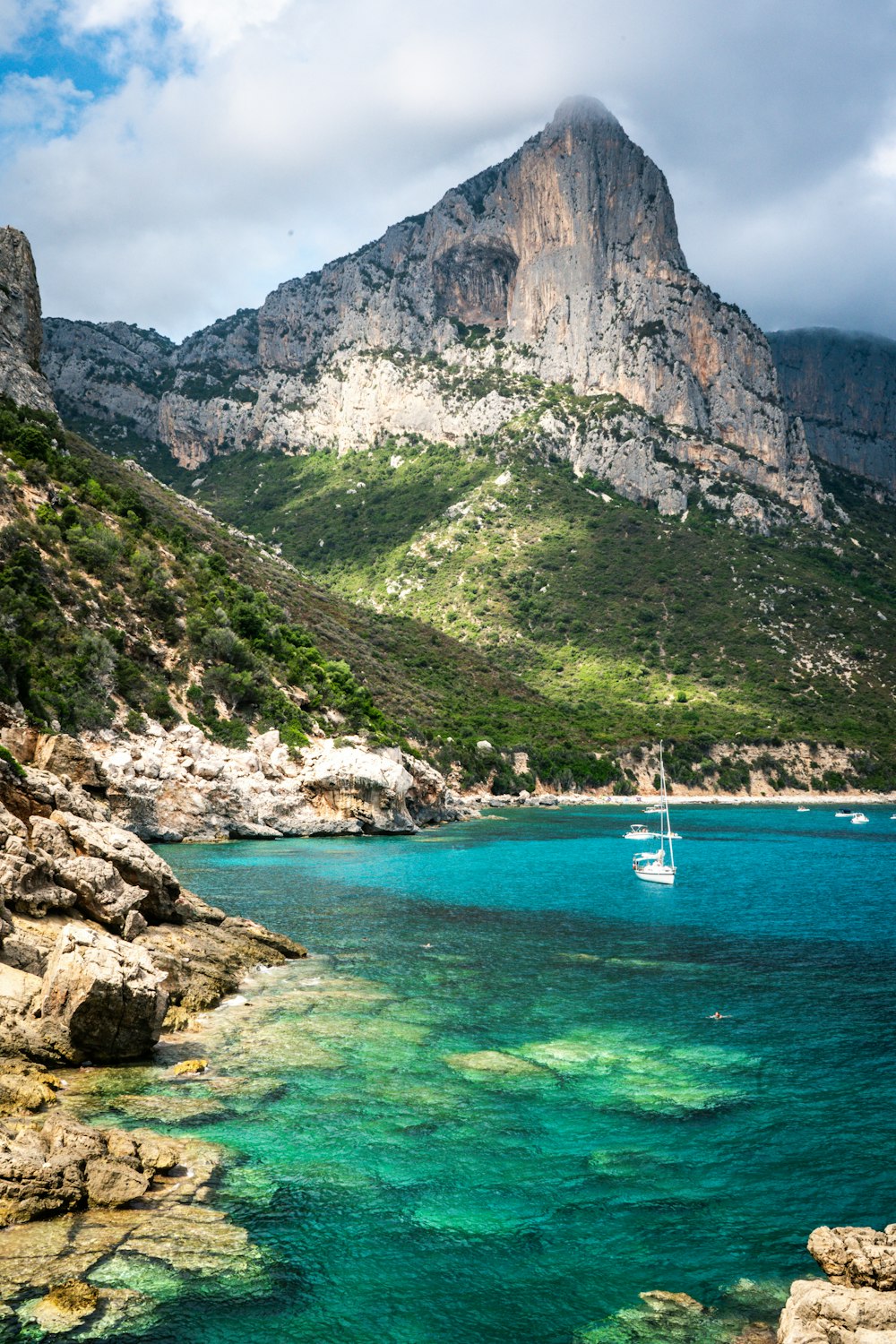 barco branco no mar perto da montanha rochosa durante o dia