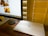 A workspace featuring a large computer monitor displaying images of dogs. Below the monitor, there's a closed Dell laptop on a wooden desk, and the scene is lit warmly by light filtering through window blinds.
