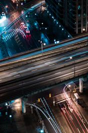 A dynamic aerial view of a bustling urban highway network at dusk, illuminated by streaks of vehicle lights.