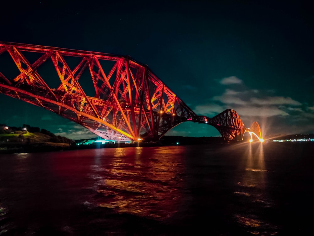 red bridge over body of water during night time