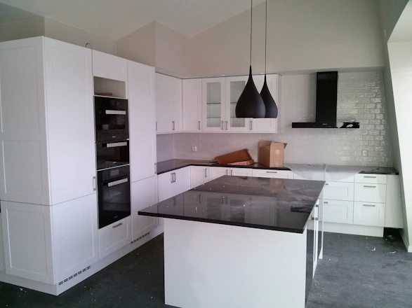 A skilled technician installing a sleek porcelain kitchen countertop in a modern Scandinavian-style kitchen.