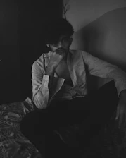 A relaxed man lying comfortably in bed with a mischievous smile, hinting at his badboy personality.