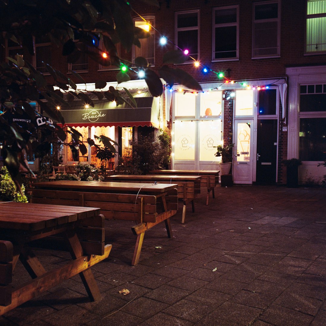 brown wooden table and chairs near white building during night time