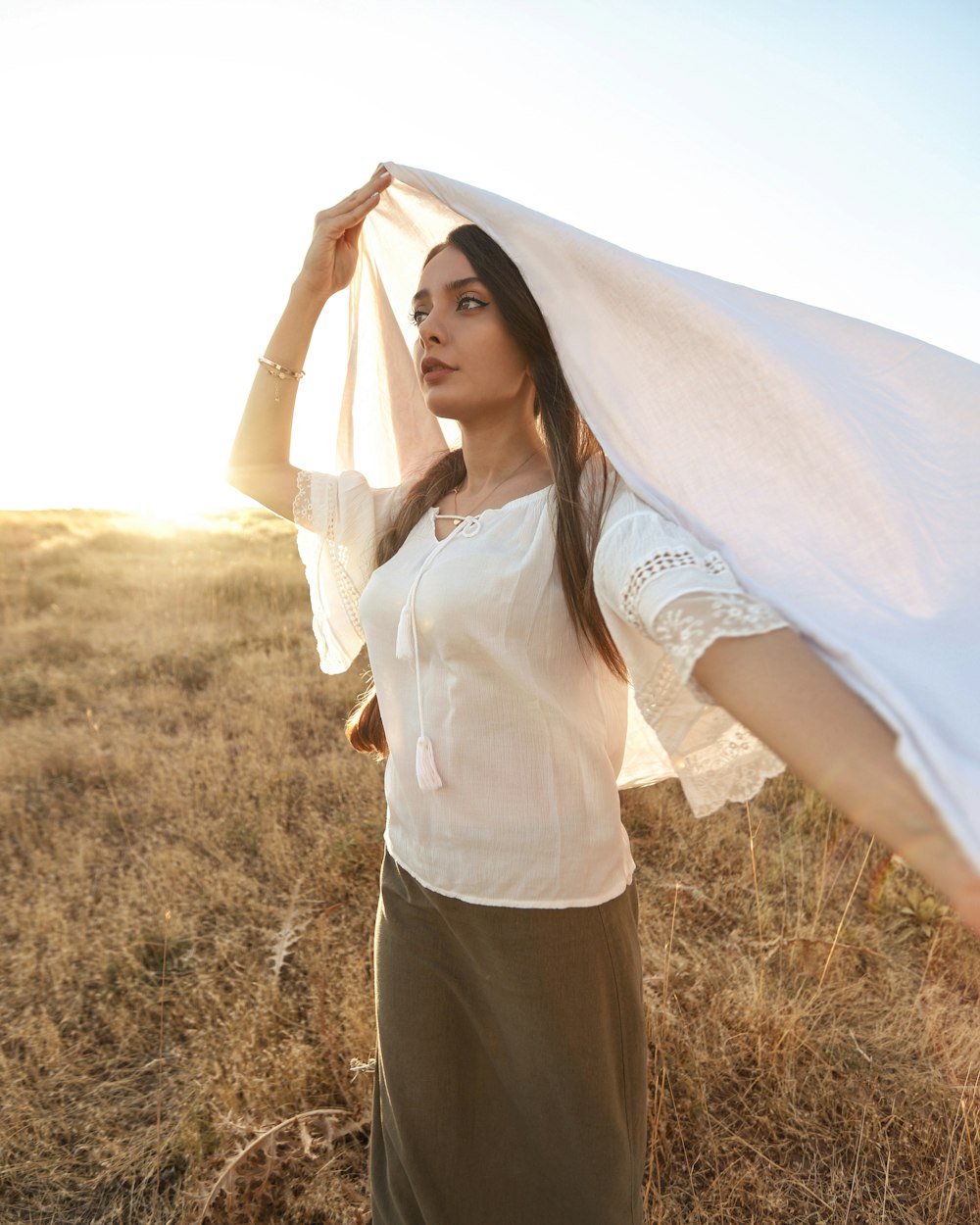 woman in white long sleeve shirt and black pants standing on brown grass field during daytime