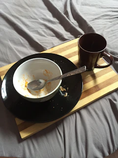 An overbed table set up with a meal tray and reading materials.