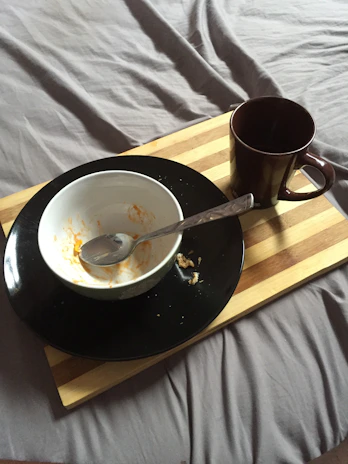 An overbed table set up with a meal tray and reading materials.