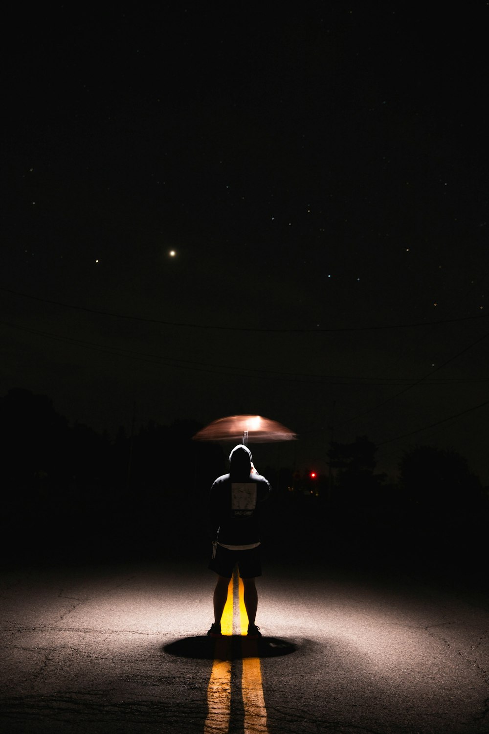 person in black jacket holding umbrella walking on street during night time