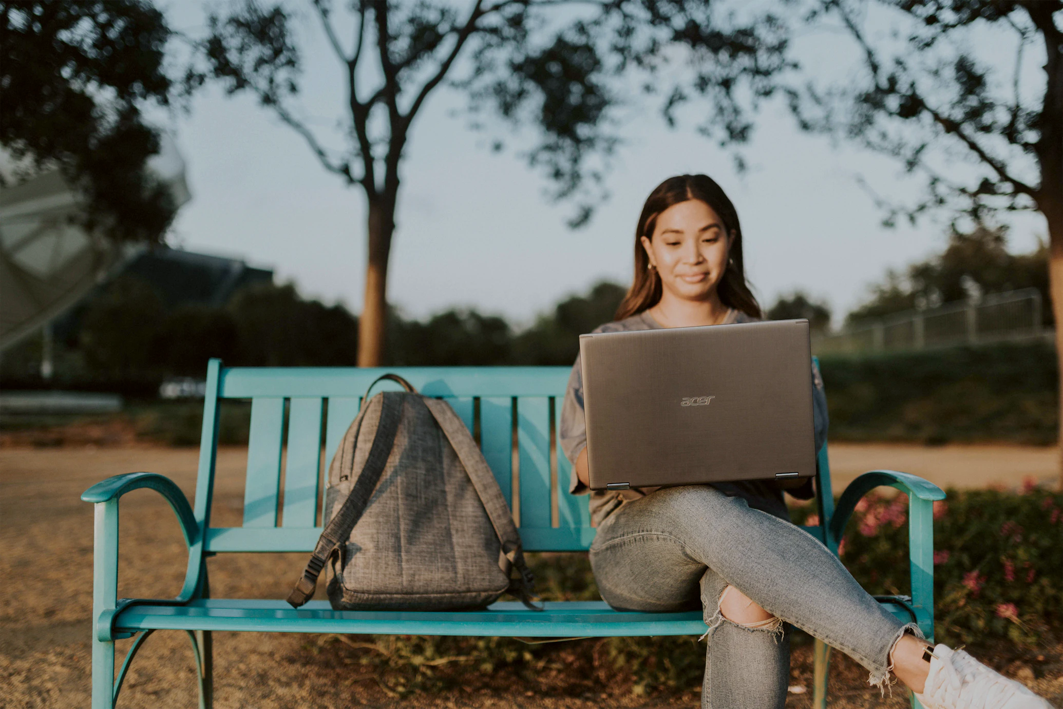 a woman sitting on a bench with a laptop