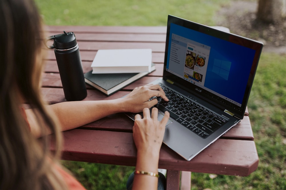 person using laptop on brown wooden table during daytime