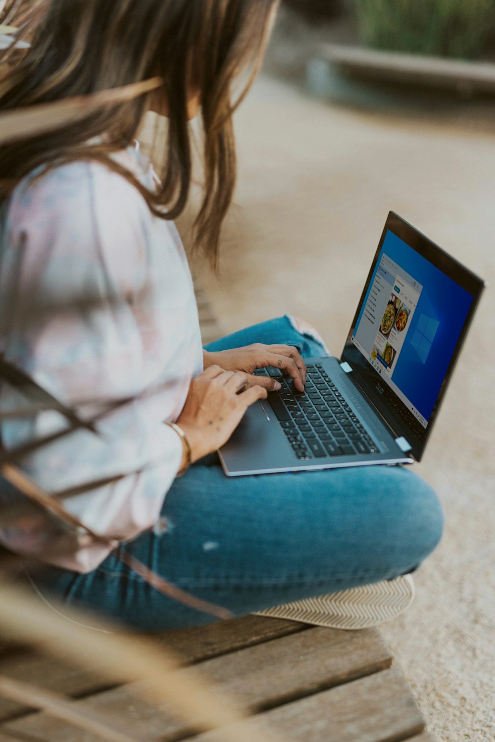 woman in white long sleeve shirt and blue denim jeans using black laptop computer