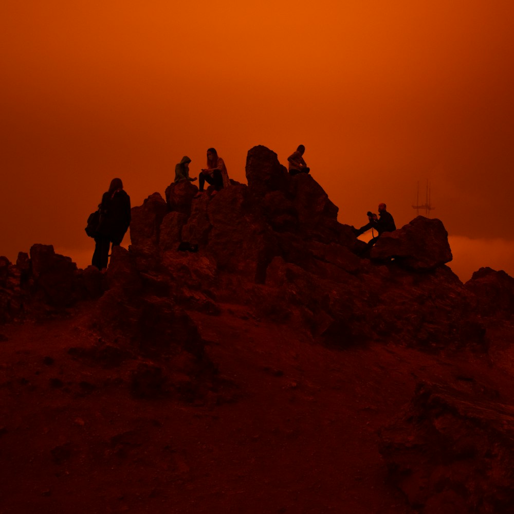 夕暮れ時の山頂の人々のシルエット