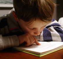 boy in gray and red hoodie reading book