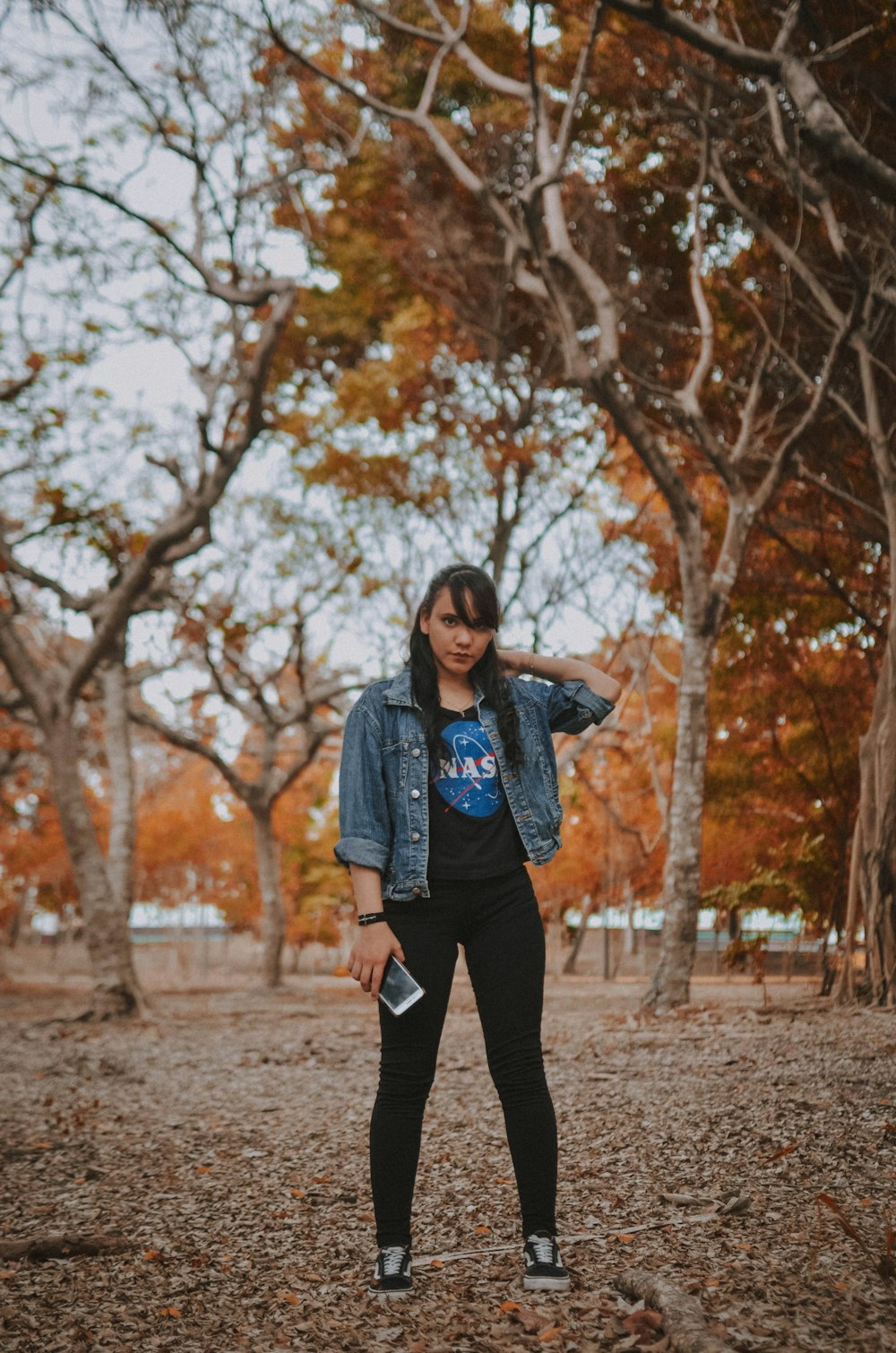 woman in brown jacket standing near brown trees during daytime