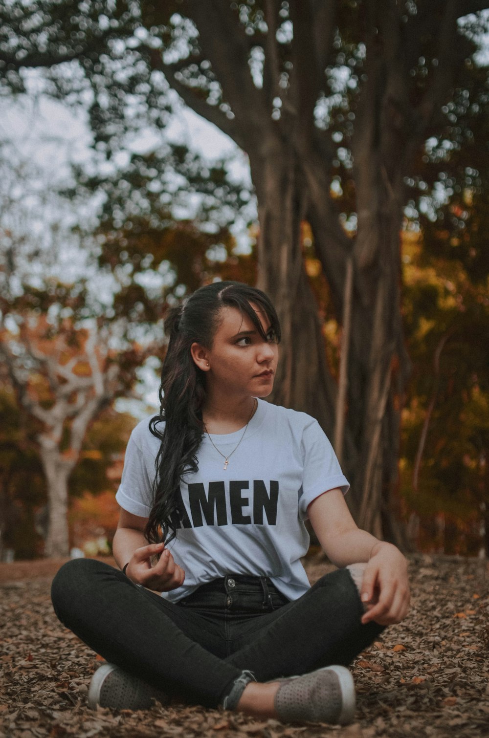 woman in white crew neck t-shirt sitting on brown rock during daytime