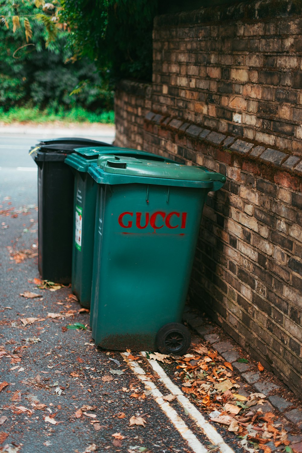 green trash bin beside brick wall