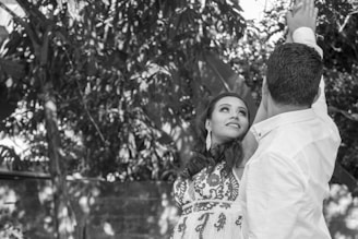 A serene black-and-white portrait of a couple embracing on a Bali beach at sunset.