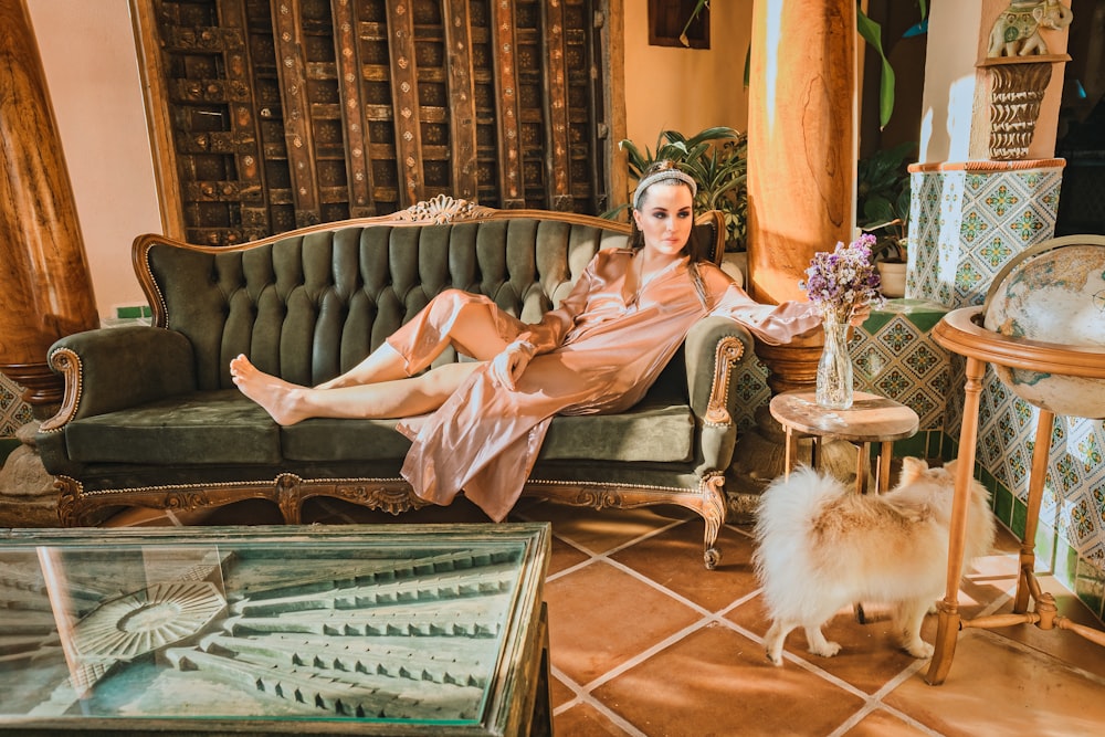 woman in pink robe sitting on green sofa