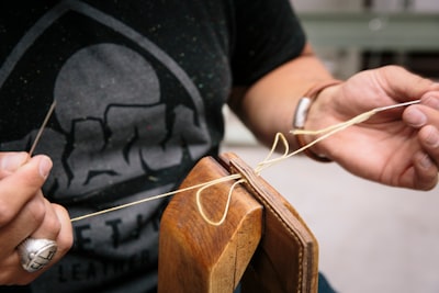 person in black crew neck t-shirt holding brown wooden guitar pick craftsman zoom background