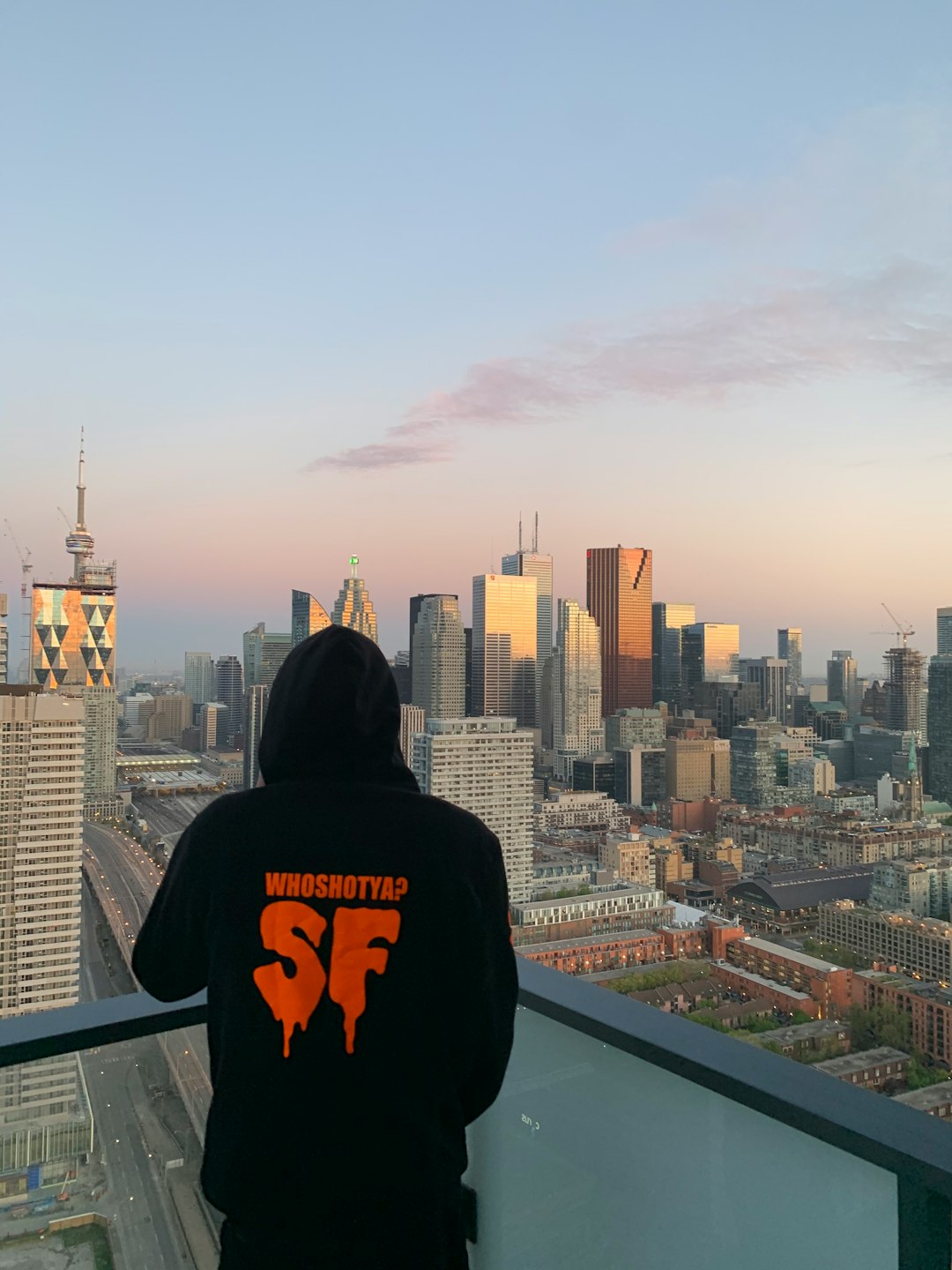 man in black hoodie sitting on top of building during daytime