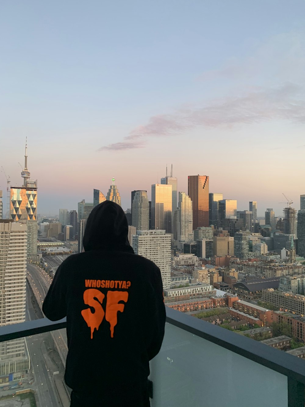 man in black hoodie sitting on top of building during daytime