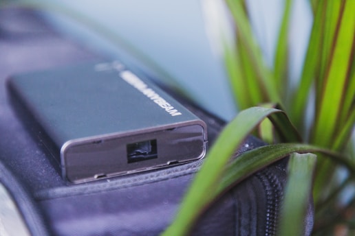 Close-up of a sleek miniaturized IoT device nestled in a lush green forest, symbolizing technology meeting nature.