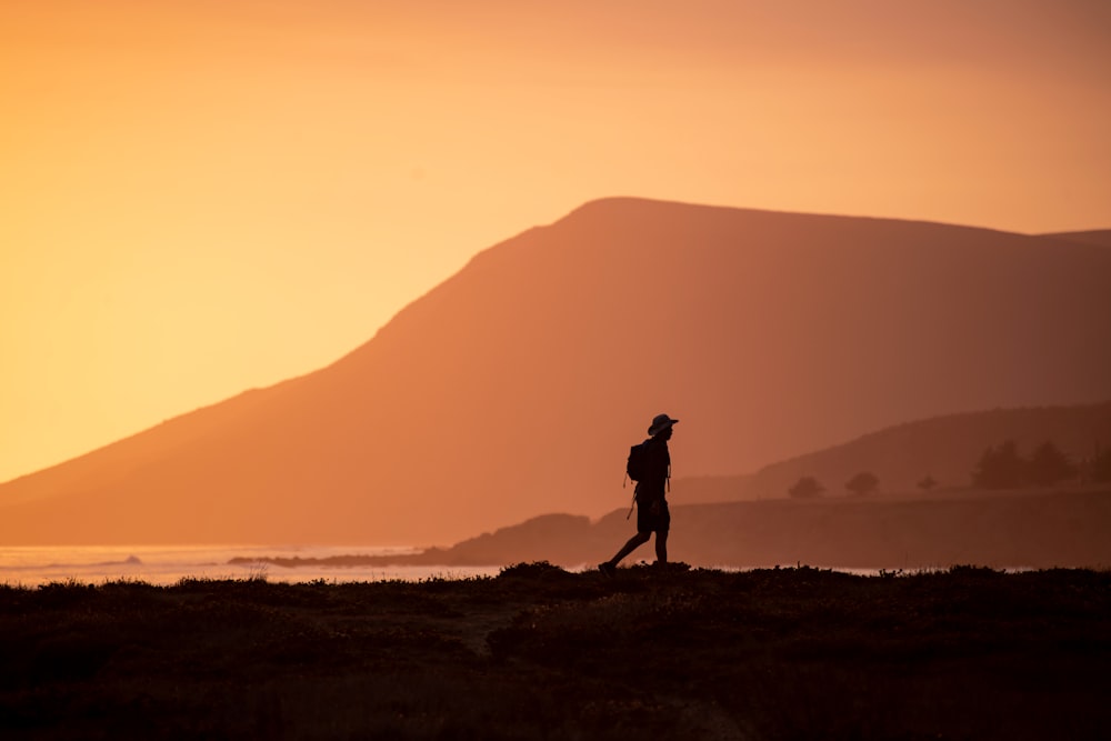 silhouette d’homme debout sur la colline pendant le coucher du soleil