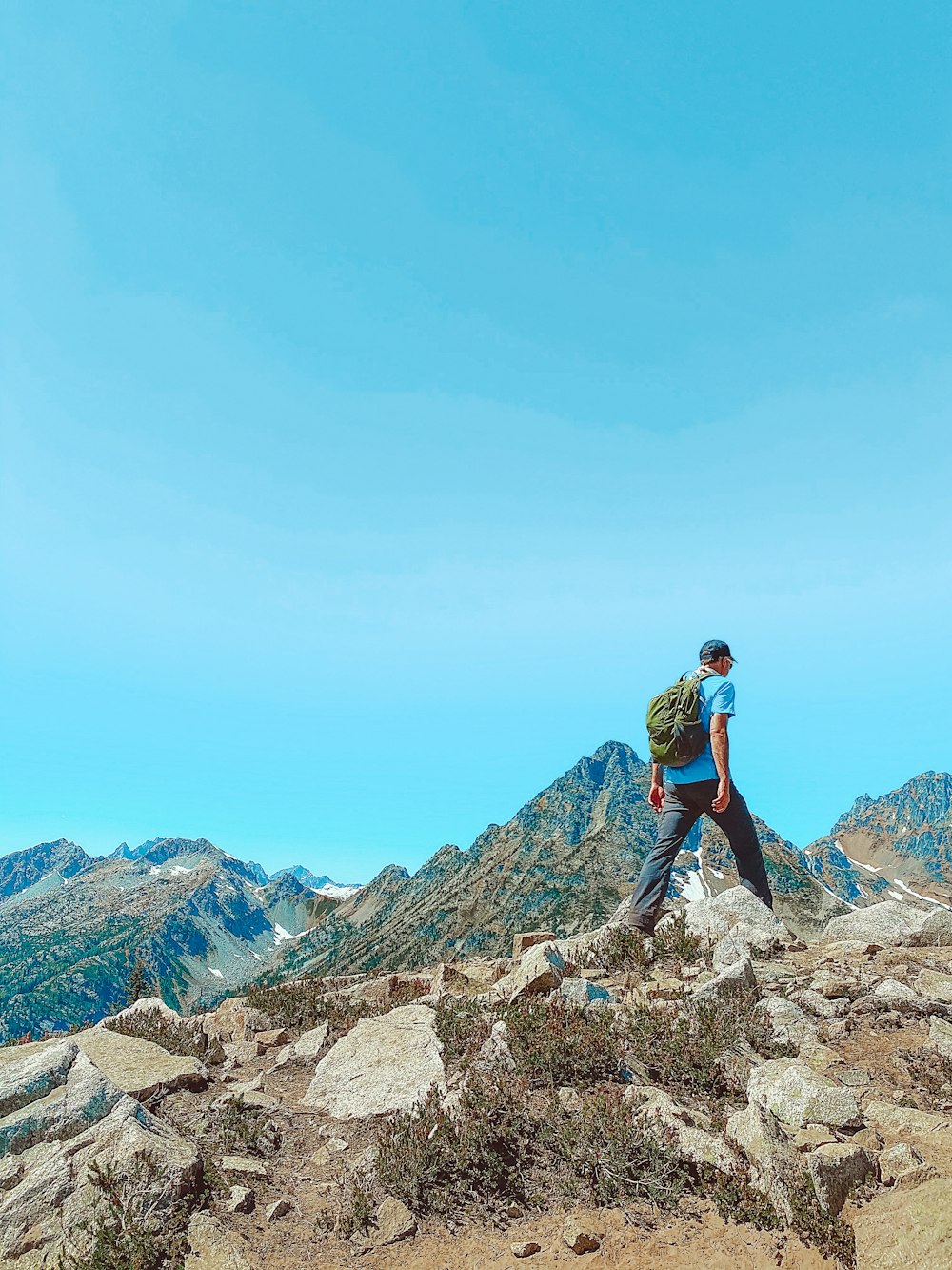 man in black jacket and blue denim jeans standing on rocky mountain during daytime