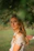woman in white and brown floral shirt standing near green leaf tree during daytime