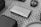 A small electronic device labeled with the words 'NEBRA ANYBEAM' lies on a patterned carpet. Surrounding it are various other electronic accessories including a power adapter.