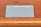 A device labeled Nebra Anybeam is placed on a wooden surface. The device is rectangular and metallic, with two ports labeled HDMI on one end. The surface it rests on is a warm-toned wood with horizontal lines.