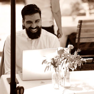 A friendly business owner happily reading positive customer reviews on a laptop.