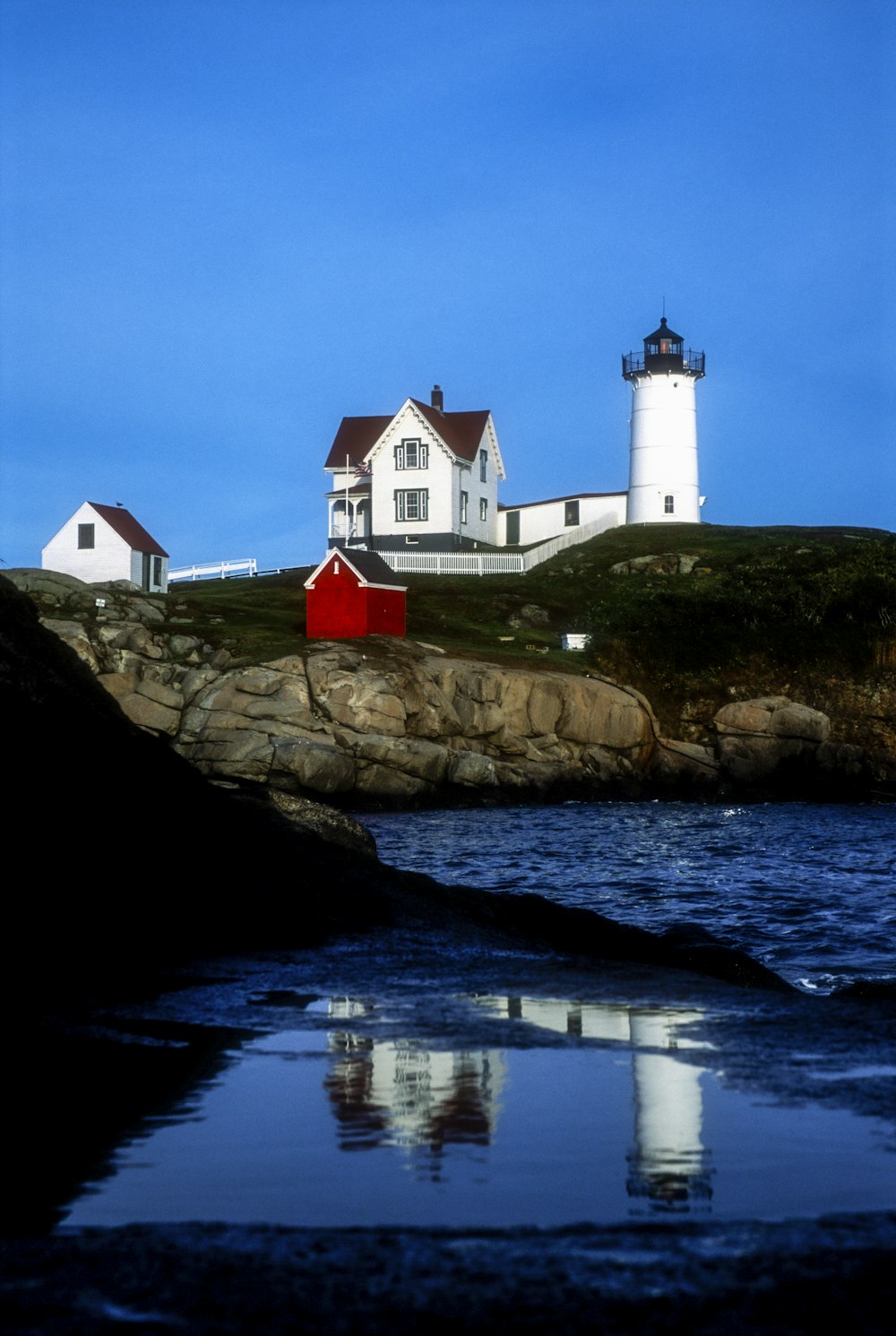 white and red house on brown rock formation beside body of water during daytime