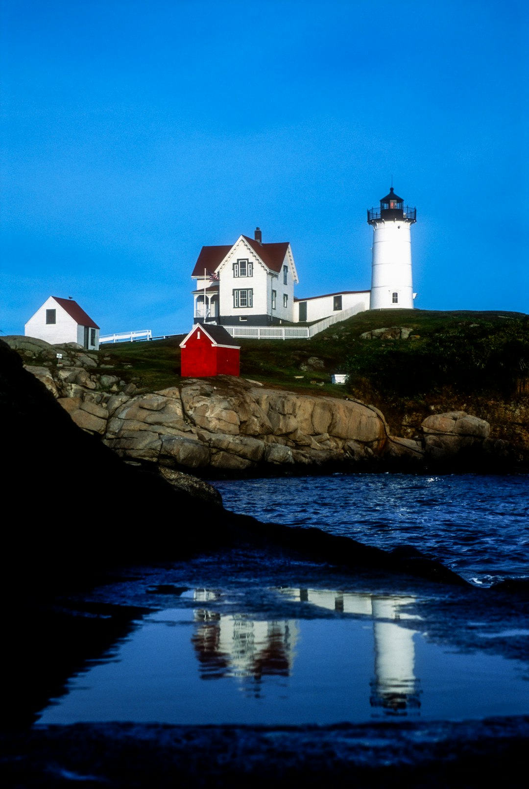 white and red house on brown rock formation beside body of water during daytime