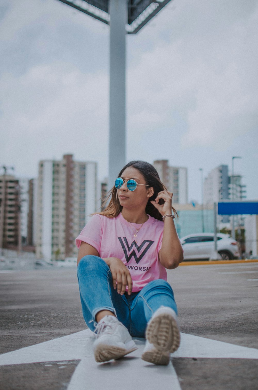woman in pink crew neck t-shirt and blue denim jeans sitting on gray concrete bench