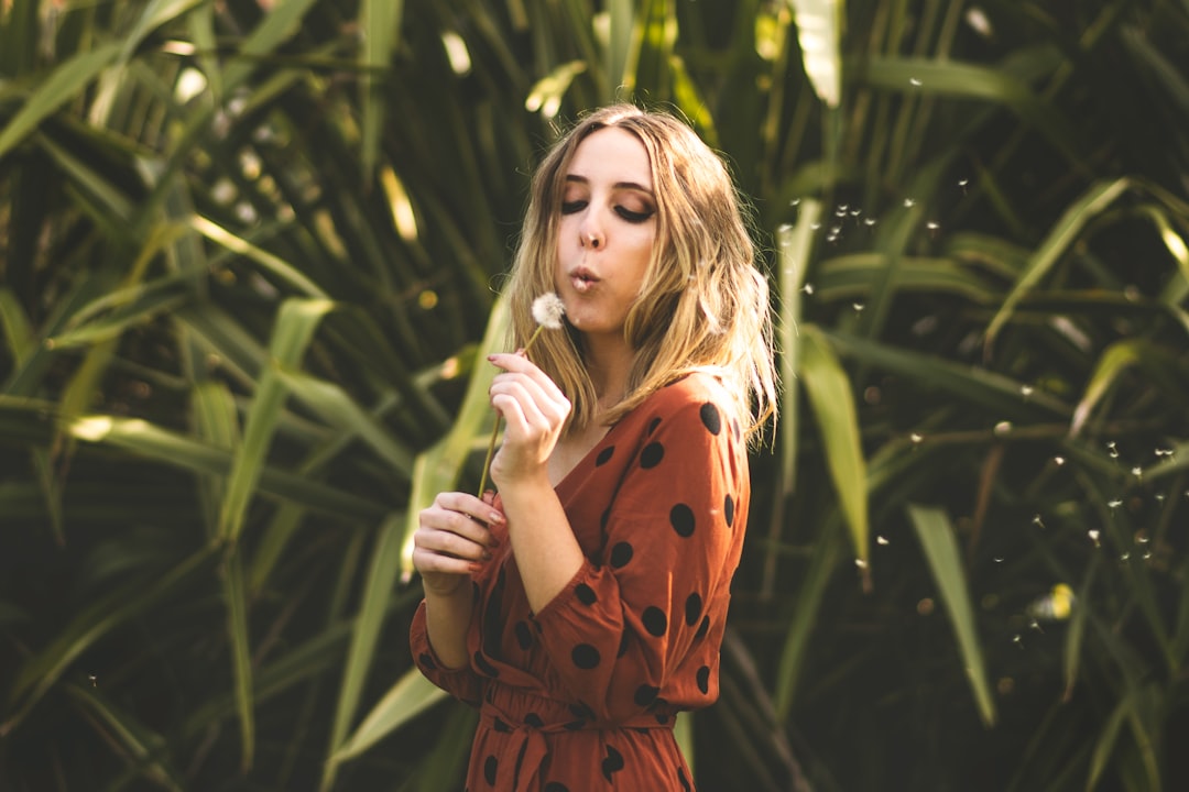 woman in orange and black polka dot dress holding green plant during daytime