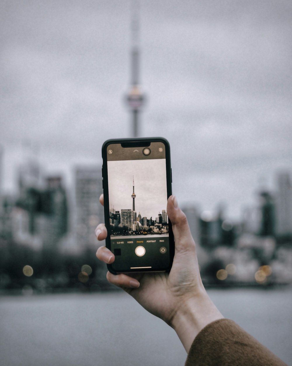 person holding black iphone 4 taking photo of city buildings during daytime