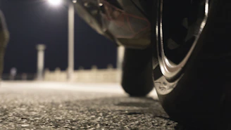 Close-up of a tire being replaced on a busy highway shoulder at dusk.