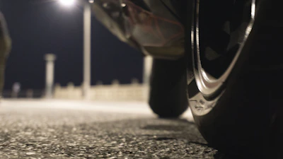 Nighttime scene of a motorbike tire being repaired on the side of a dimly lit road.