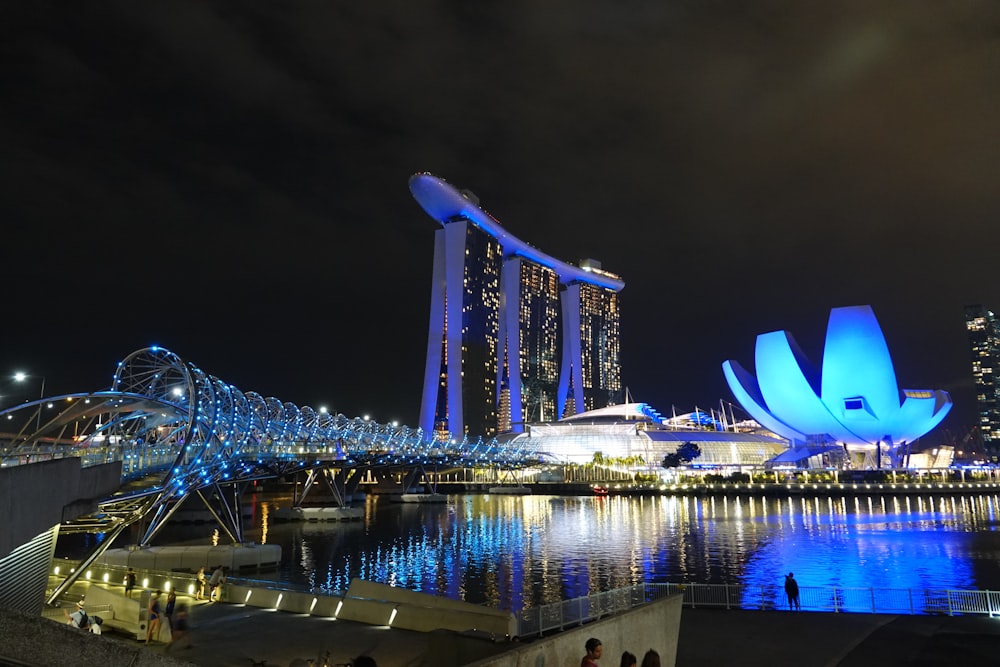 people walking on bridge near city buildings during night time