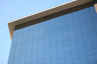A sleek modern office window reflecting a clear blue sky with subtle cityscape hints.