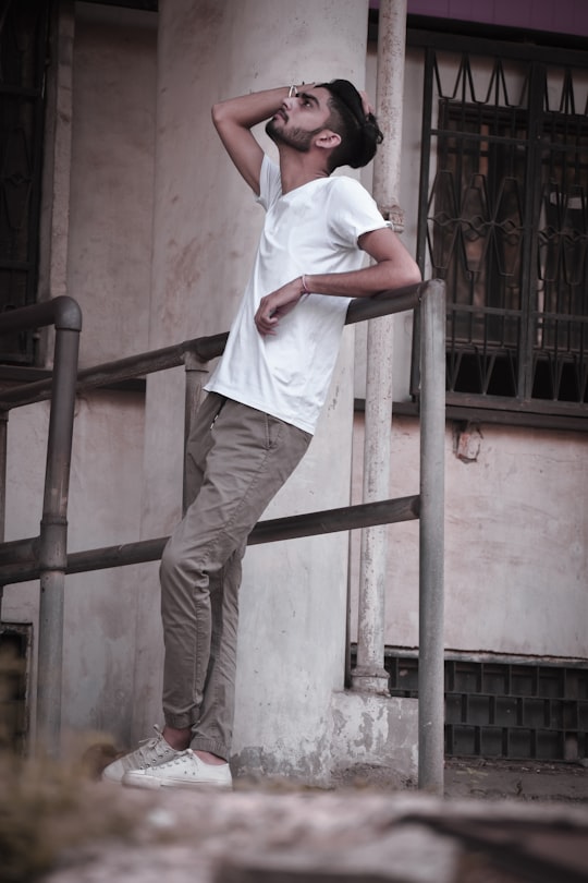 man in white t-shirt and brown pants standing on brown wooden ladder in Chandigarh India