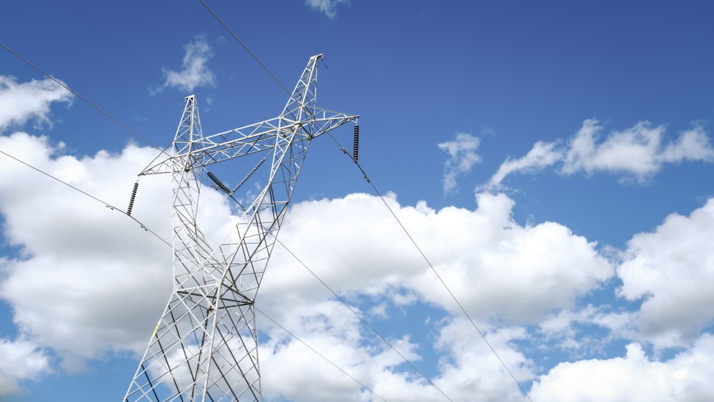 black electric tower under blue sky and white clouds during daytime