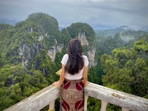 woman in red and white floral dress standing on wooden bridge during daytime