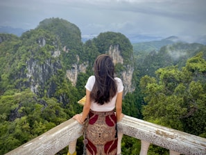 woman in red and white floral dress standing on wooden bridge during daytime